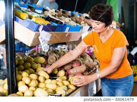 Smiling female is choosing potato in the supermarket. 88061479