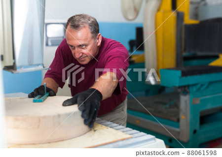 Elderly worker fixes wooden workpiece in 3d machine Elderly worker fixes wooden workpiece in 3d machine 88061598