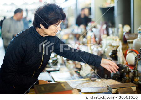 interested elderly woman choosing interesting souvenirs at flea market 88061616