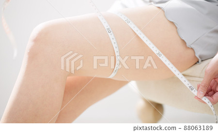 A beauty image of a woman who measures the size of her thighs with a tape measure 88063189