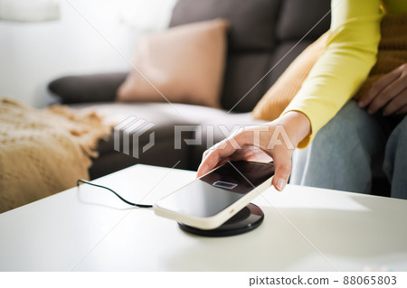 Charging mobile phone battery with wireless charging device in the table. Smartphone charging on a charging pad. Mobile phone near wireless charger Modern lifestyle technology concept. 88065803
