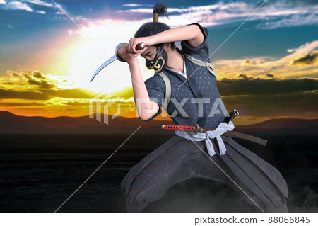 A samurai wearing a fox mask against the Asahi is swinging his sword and training. 88066845