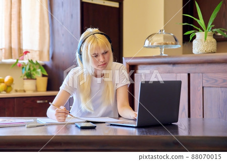 Teenage female student studying at home using a laptop. Teenage female student studying at home using a laptop. 88070015