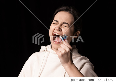 Half-legth portrait of young emotional girl rips three colors duct tape off her mouth isolated on dark background. Censorship, freedom of speech concept. Half-legth portrait of young emotional girl rips three colors duct tape off her mouth isolated on dark background. Censorship, freedom of speech concept. 88071729