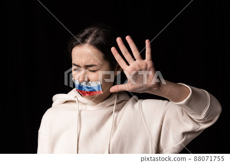 Half-legth portrait of young emotional upset girl with three colors duct tape over her mouth isolated on dark background. Censorship, freedom of speech concept. Half-legth portrait of young emotional upset girl with three colors duct tape over her mouth isolated on dark background. Censorship, freedom of speech concept. 88071755