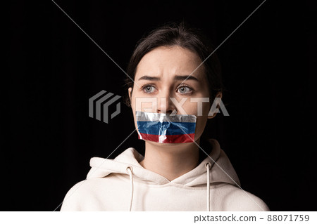 Half-legth portrait of young emotional upset girl with three colors duct tape over her mouth isolated on dark background. Censorship, freedom of speech concept. Half-legth portrait of young emotional upset girl with three colors duct tape over her mouth isolated on dark background. Censorship, freedom of speech concept. 88071759