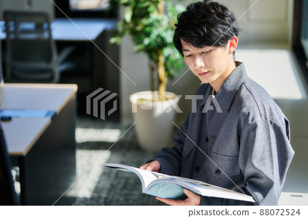 Young man reading a book by the window 88072524