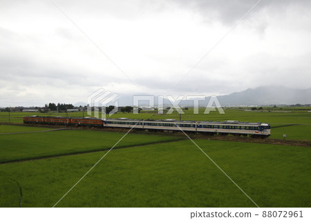 越後線 115 系列 6 車穿過多雲的新潟平原 88072961