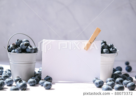 Blueberries in a small Bucket on concrete background with empty paper note. Healthy organic seasonal fruit background. Organic food. Healthy summer snack. Copy space Superfood 88073372