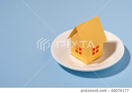 Close-up of a small yellow house made of paper on a plate Close-up of a small yellow house made of paper on a plate 88076177