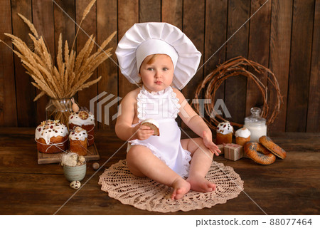 A little funny girl in a white cook suit on a dark wooden background 88077464
