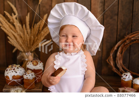 A little funny girl in a white cook suit on a dark wooden background 88077466