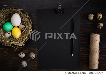 Easter eggs in nest, scissors and thread on a black background Easter eggs in nest, scissors and thread on a black background 88078274