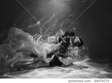 A romantic couple kissing underwater in swimming pool wearing clothes A romantic couple kissing underwater in swimming pool wearing clothes 88078570