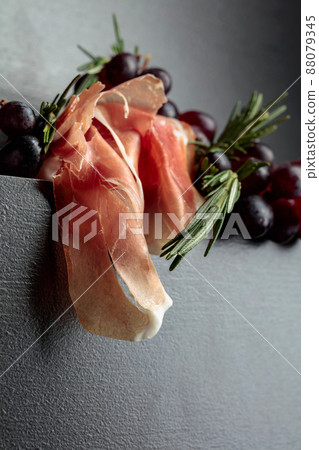 Prosciutto with red grapes and twigs of rosemary. Prosciutto with red grapes and twigs of rosemary. 88079345