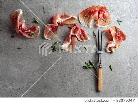 Prosciutto with rosemary on an old concrete background. Prosciutto with rosemary on an old concrete background. 88079347