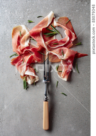 Prosciutto with rosemary on an old concrete background. Prosciutto with rosemary on an old concrete background. 88079348