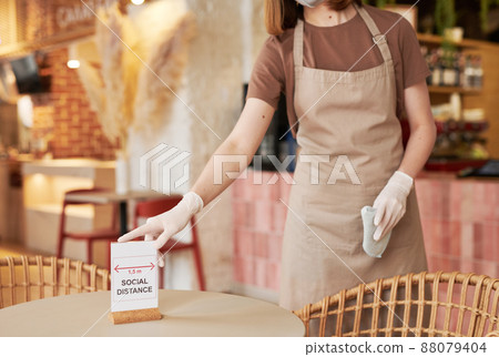 Unrecognizable female cafe worker putting social distance sign on table, copy space Unrecognizable female cafe worker putting social distance sign on table, copy space 88079404