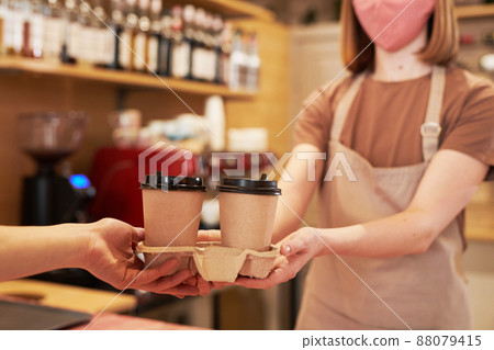 Medium section selective focus shot of unrecognizable female cafe worker standing at counter giving two cups of coffee to customer Medium section selective focus shot of unrecognizable female cafe worker standing at counter giving two cups of coffee to customer 88079415