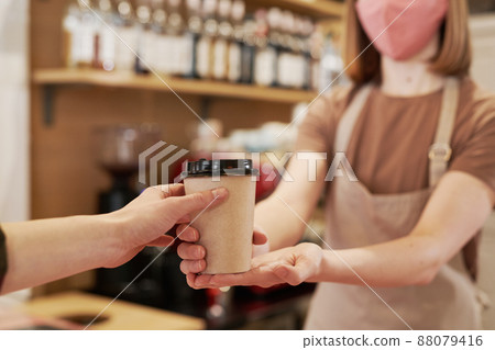 Medium section selective focus shot of unrecognizable female barista standing at cafe counter giving cup of coffee to customer 88079416