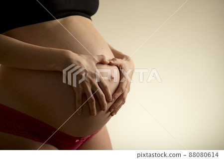 Pregnant woman holding her bare belly 88080614