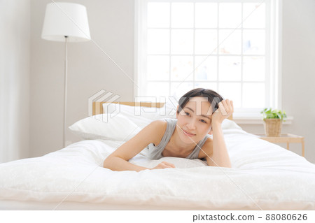 A woman lying on a futon and smiling. A woman lying on a futon and smiling. 88080626
