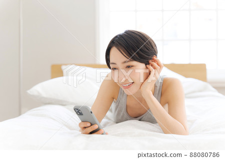 躺在床上的女性智能手機 躺在床上的女性智能手機 88080786