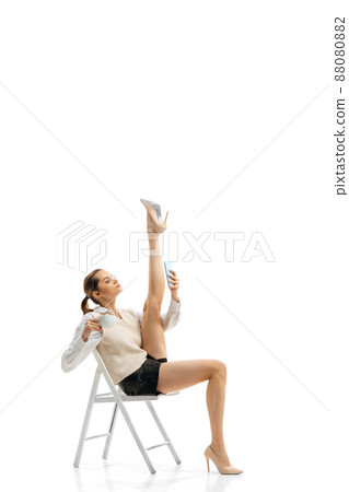 Portrait of young pretty girl, office worker in stylish cloth sitting, having online video call isolated over white studio background. Twine 88080882