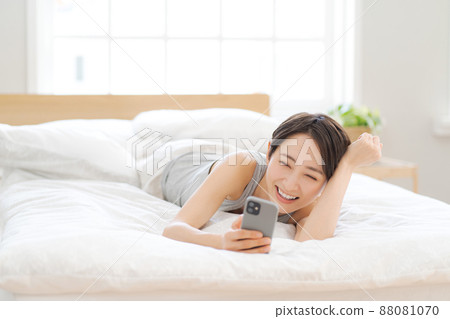 Female smartphone lying on the bed Female smartphone lying on the bed 88081070