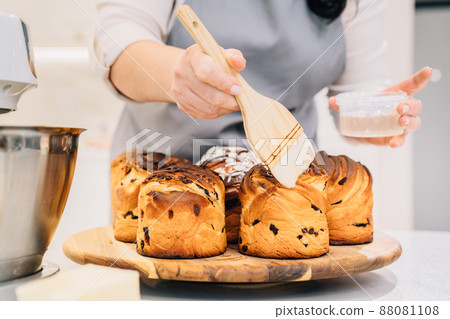 a female cook lubricates with melted butter a Kraffin, easter cake 88081108