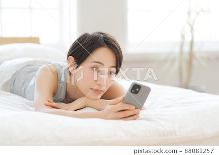 Female smartphone lying on the bed Female smartphone lying on the bed 88081257
