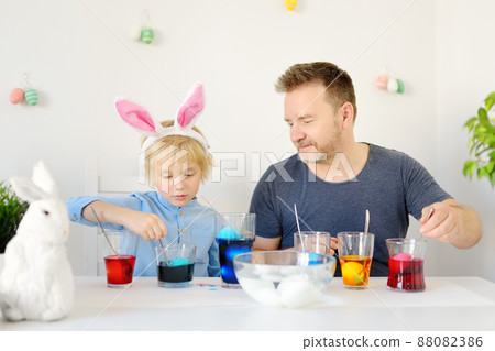 Mature father and her son are painting eggs for Easter. Happy family preparing for Easter. Mature father and her son are painting eggs for Easter. Happy family preparing for Easter. 88082386