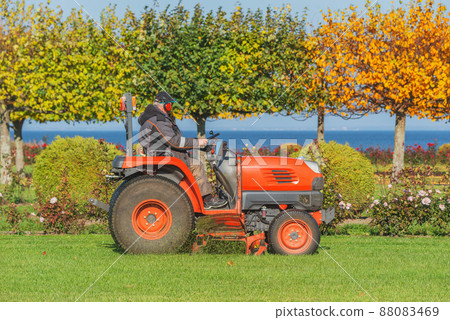 Man mows the grass in the city park at sunny day time. Man mows the grass in the city park at sunny day time. 88083469