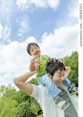 Father and son playing on each other's shoulders in the park 88084203