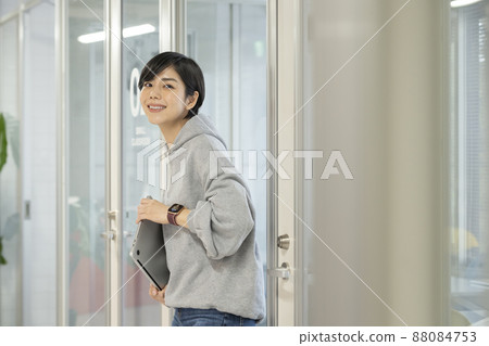 A casual business image of a young woman with a smiling face looking at the camera with a laptop computer 88084753