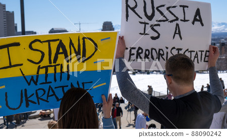 People holding signs, Russia is a terrorist state, I stand with Ukraine, at pro Ukraine rally in the United States with crowd and city in background blur People holding signs, Russia is a terrorist state, I stand with Ukraine, at pro Ukraine rally in the United States with crowd and city in background blur 88090242