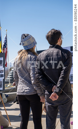 Young couple in winter clothes at pro Ukraine rally in United States at Utah State Capitol building. Ukrainian and US flags at side. High quality photo 88090244
