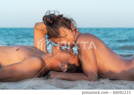 Naked beloved couple lying on beach and embracing 88092215