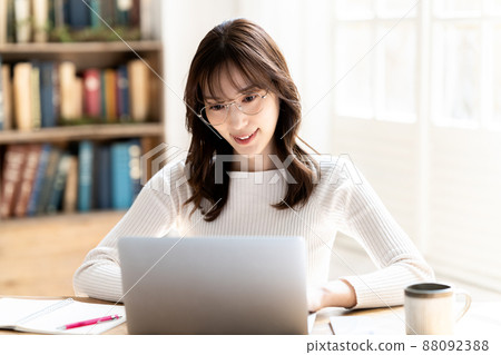 Woman with glasses using a laptop in the room Woman with glasses using a laptop in the room 88092388