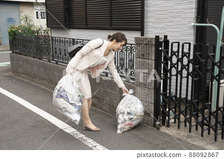 A woman who takes out the trash before going to work 88092867