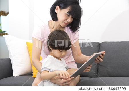 young asian mother and son sitting on sofa using digital tablet happy and smiling. young asian mother and son sitting on sofa using digital tablet happy and smiling. 88093299