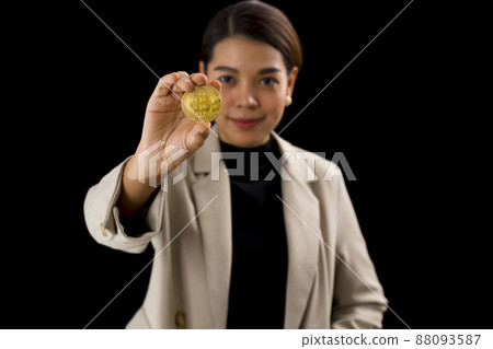 Crypto currency, web money and blockchain concept - Asian woman in formal dress hold bitcoin in her hand on black background. Crypto currency, web money and blockchain concept - Asian woman in formal dress hold bitcoin in her hand on black background. 88093587