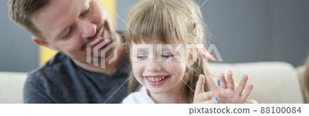 Dad playing with little daughter sitting on the couch 88100084