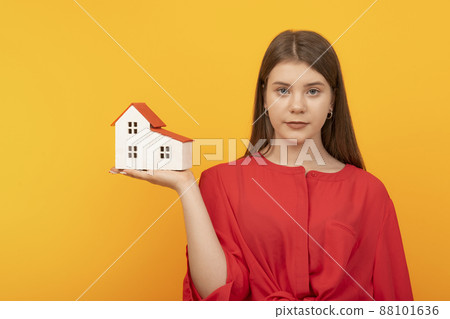 Young pretty woman holds model of house on bright orange background. House insurance concept. Real estate for young families, mortgage Young pretty woman holds model of house on bright orange background. House insurance concept. Real estate for young families, mortgage 88101636