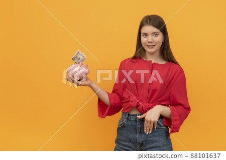 Young woman or teenage girl holds piggy bank with money in hands. Financial planning, savings. Financial literacy concept Young woman or teenage girl holds piggy bank with money in hands. Financial planning, savings. Financial literacy concept 88101637