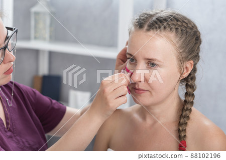 Cosmetologist sticks tapes on the girls face. Facelift. Tape for facelift with kinezio. Aesthetic patch for face. 88102196