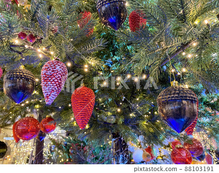 Green branches of a fluffy Christmas festive New Year tree with toys in balls and bright glowing light bulbs and garlands, background Green branches of a fluffy Christmas festive New Year tree with toys in balls and bright glowing light bulbs and garlands, background 88103191
