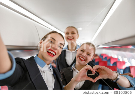 Cheerful flight attendants having fun in airplane Cheerful flight attendants having fun in airplane 88103806