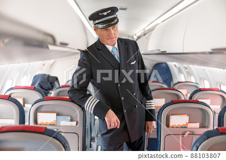 Man airline captain standing in passenger airplane cabin 88103807
