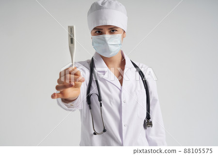 Young female doctor showing thermometer over white background, studio shot Young female doctor showing thermometer over white background, studio shot 88105575